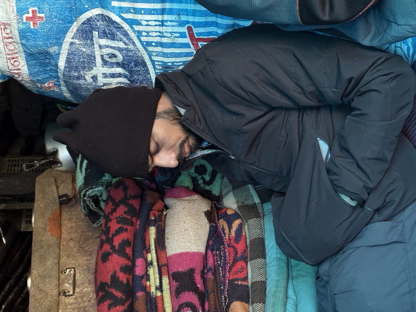 A trekker taking a quick nap beside folded blankets at the Laka food shelter